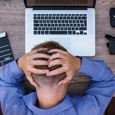 Fáradt, fájdalmakkal küzdő férfi Fájdalmakkal küzdő, fáradt férfi fogja a fejét a laptop felett